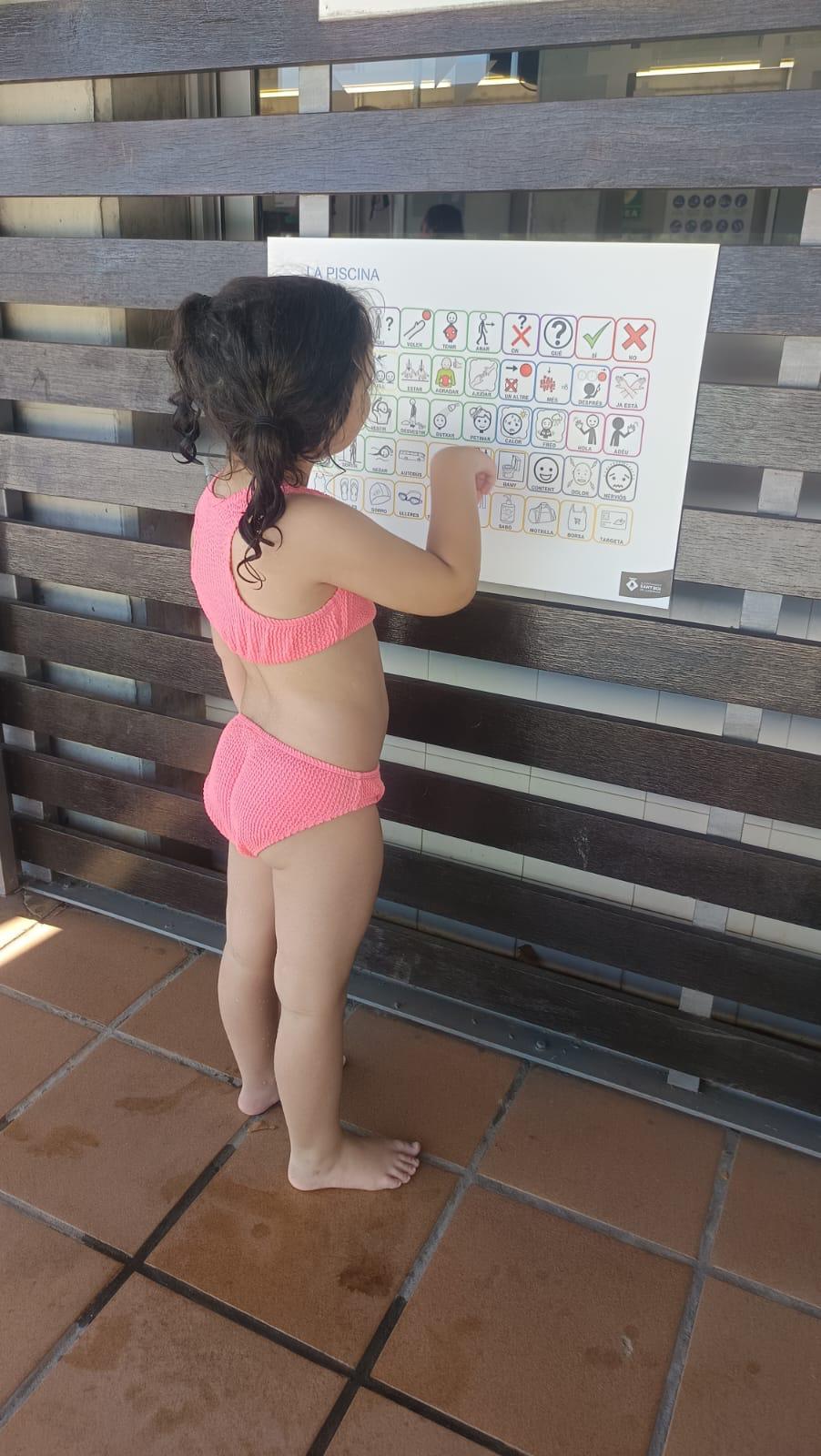 Niña utilizando un panel de pictogramas en la piscina